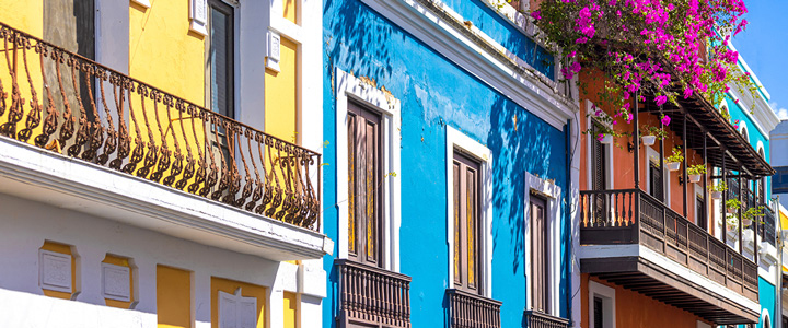 Die historische Altstadt von San Juan zeigt farbenfrohe Fassaden in Gelb, Blau und Orange. Holzbalkone, Sprossenfenster und schmiedeeiserne Geländer prägen das Stadtbild.